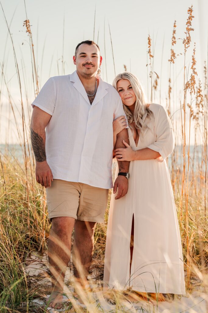 Couple posed in sea oats at Pass-a-Grille Beach during their engagement session.