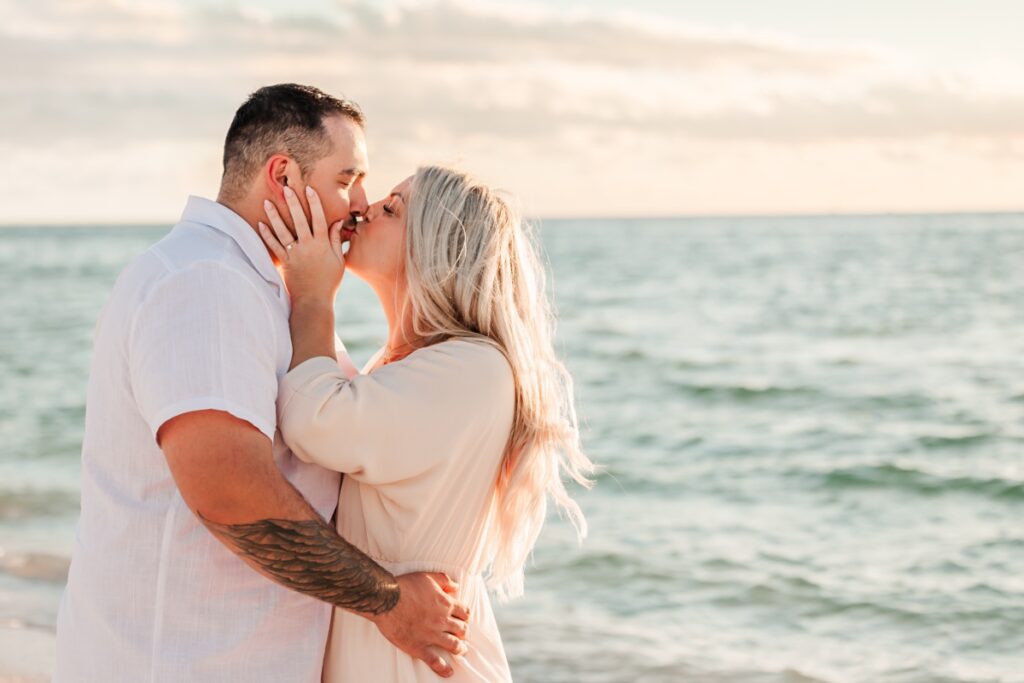 Taylor and Grant sharing a kiss as the sun sets over Pass-a-Grille Beach during their engagement session.