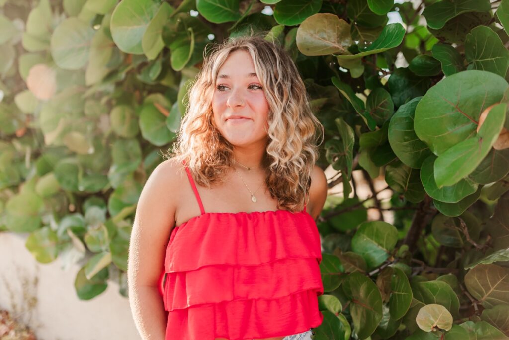 Senior girl in bright top posing with Seagrape tree in St. Petersburg, Florida.