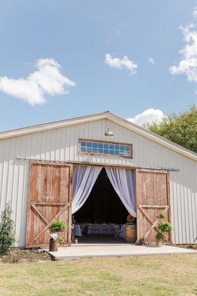White rustic barn with large wooden doors at The Barn at Azalea Oaks.